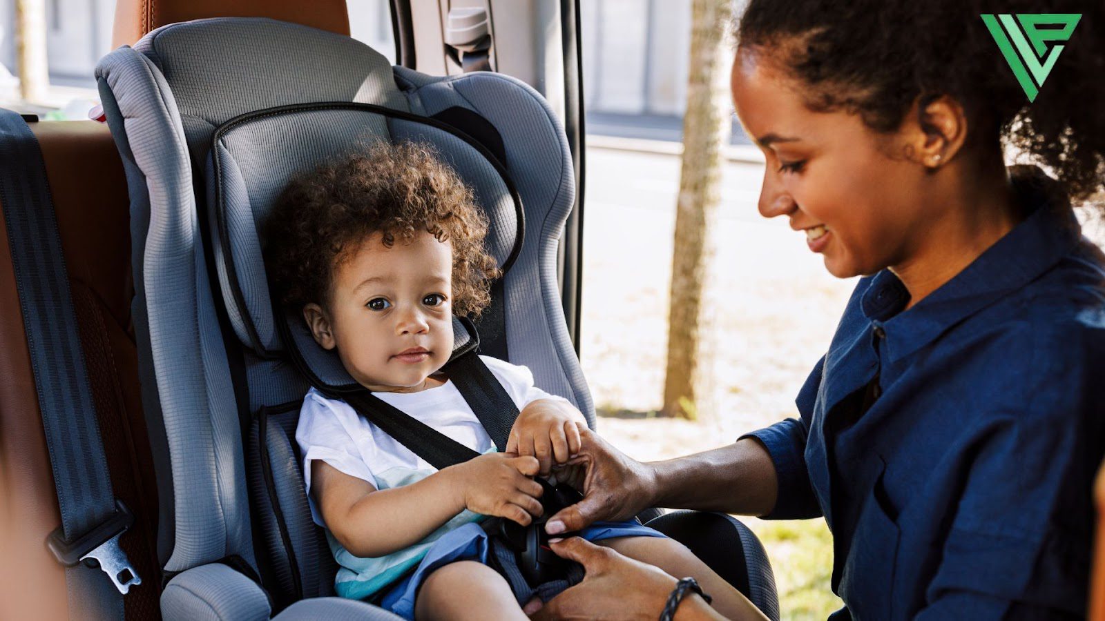 A lady is buckling a toddler into a forward facing car seat. 
