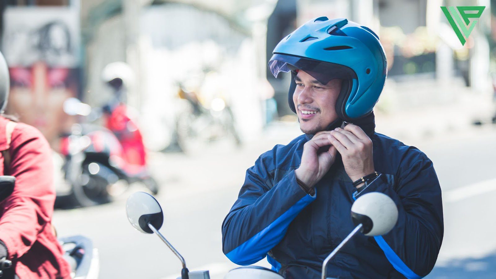 A motorcyclist sits on his bike and buckles on his helmet to protect himself from hazards on the road.