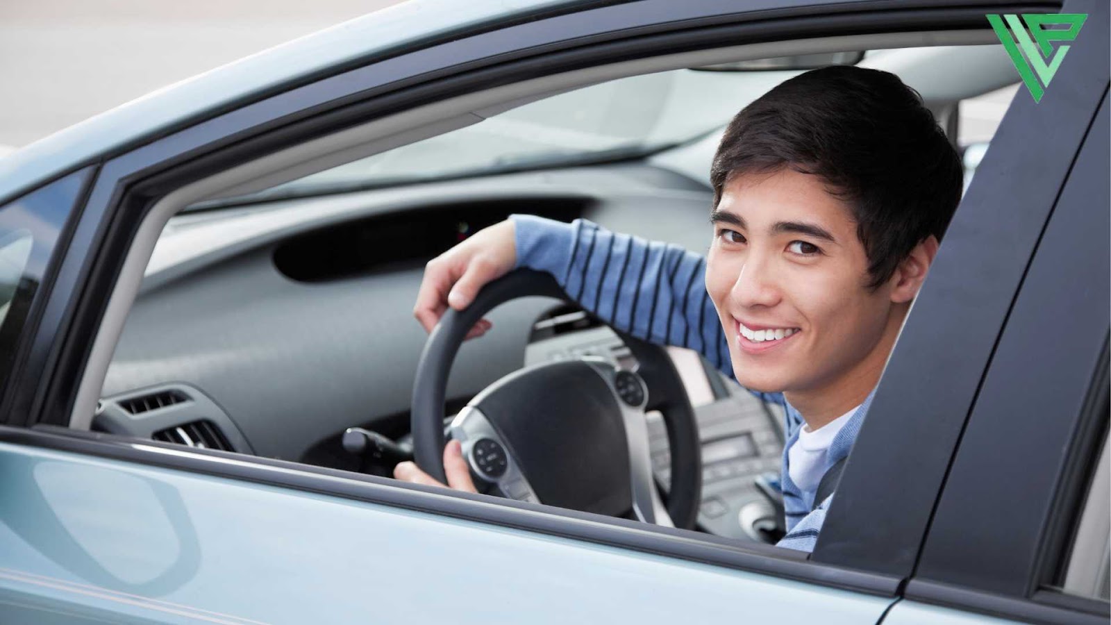 A teenage boy is seated in the driver’s seat of a car, smiling toward the camera, indicating that he has reached the legal driving age in Florida.